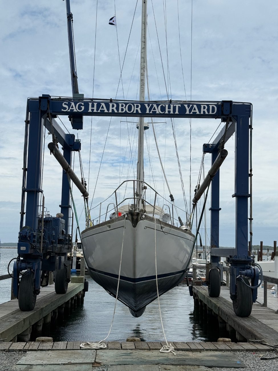A classic yawl in the travel lift slings at a boatyard
